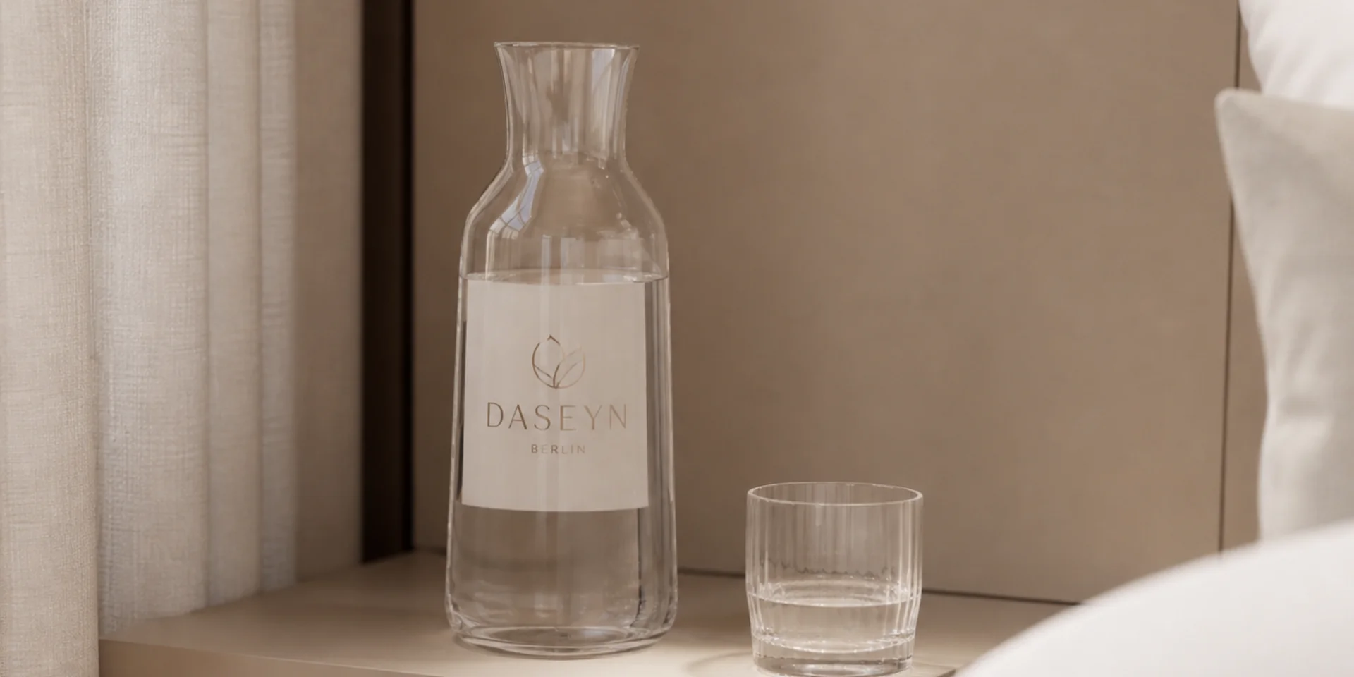 Ein nachhaltiges Hotel in Deutschland: das DASEYN Glaskaraffe mit Wasser und Glas auf Nachttisch neben Bett