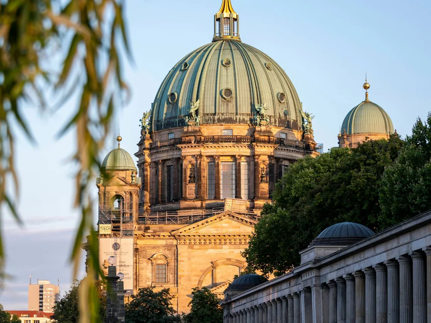 Berliner Sehenswürdigkeiten Berliner Dom mit Flussufer und blauem Himmel im Abendlicht