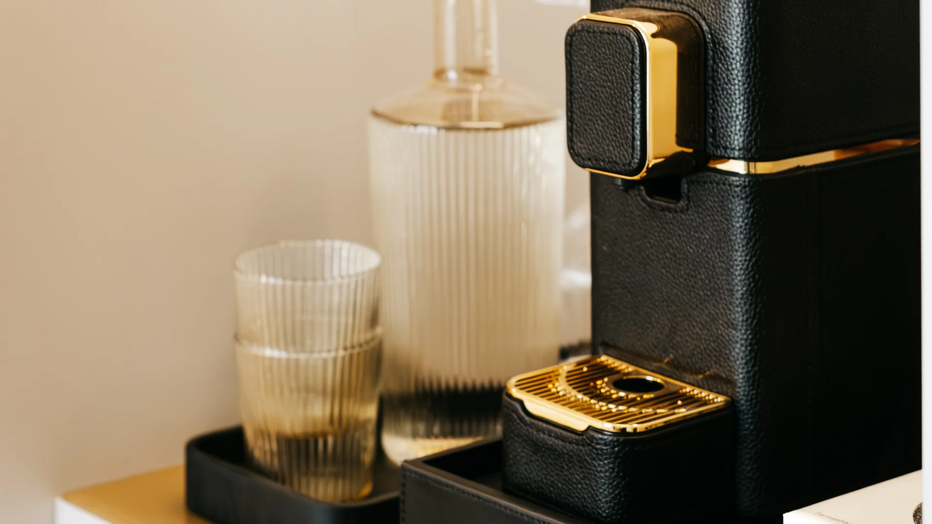 Bilder aus dem DASEYN Schwarze Kaffeemaschine mit goldenen Akzenten und Gläsern auf einem weißen Sideboard