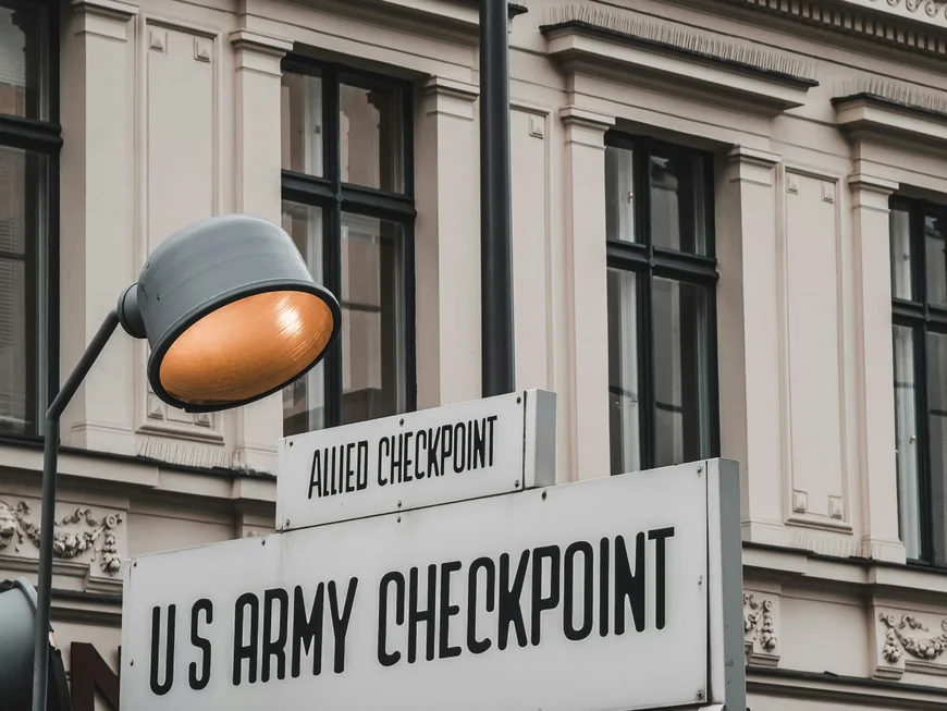 Berliner Sehenswürdigkeiten Leuchtturm und Schild am historischen US-Army Checkpoint mit Gebäude im Hintergrund