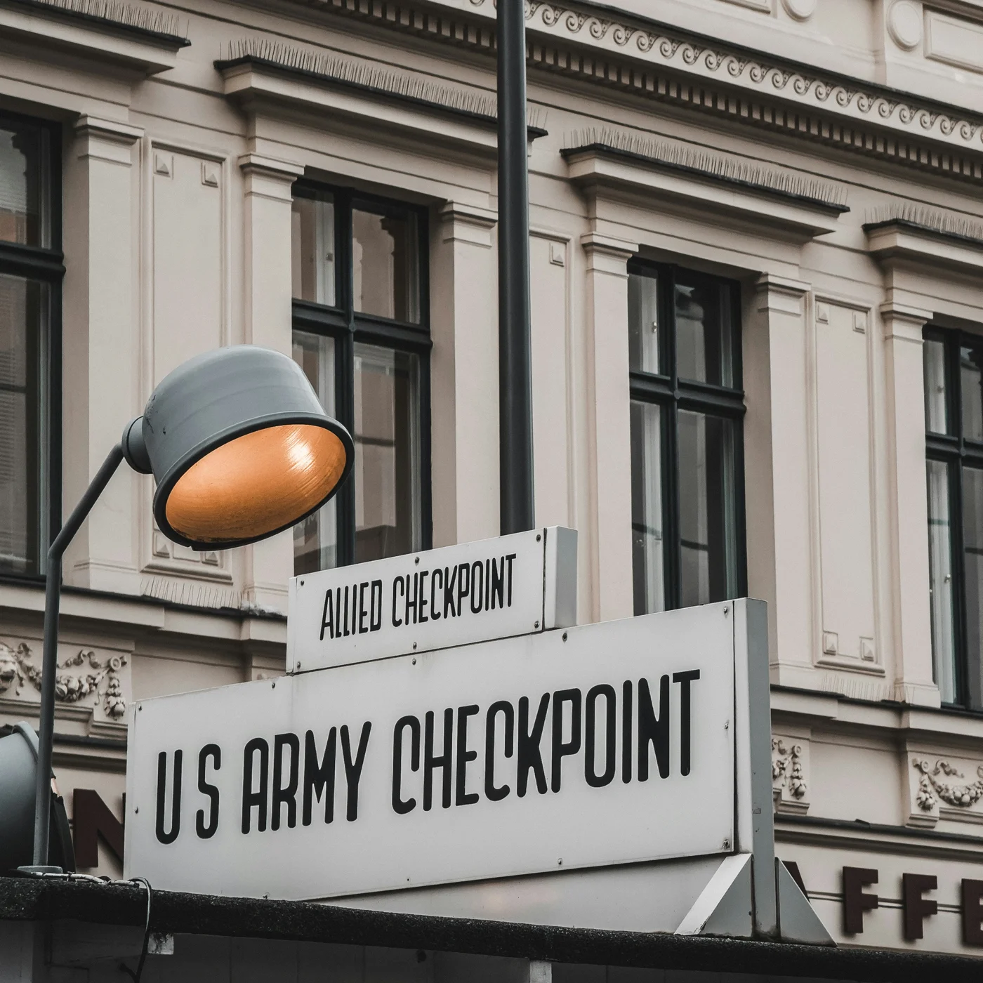 Berliner Sehenswürdigkeiten Leuchtturm und Schild am historischen US-Army Checkpoint mit Gebäude im Hintergrund