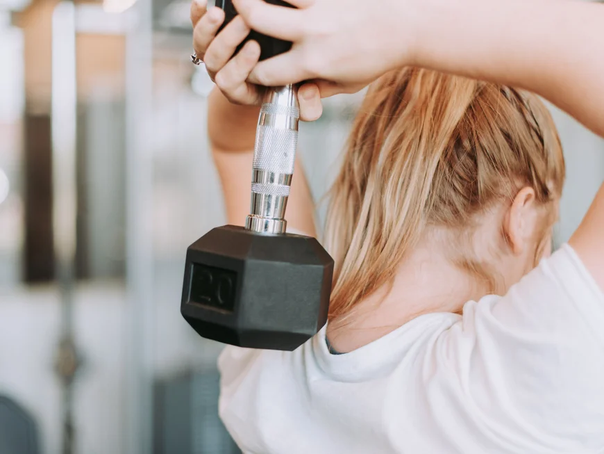 Auf ins Gym in Berlin-Mitte Blonde Frau hebt eine Hantel im Fitnessstudio