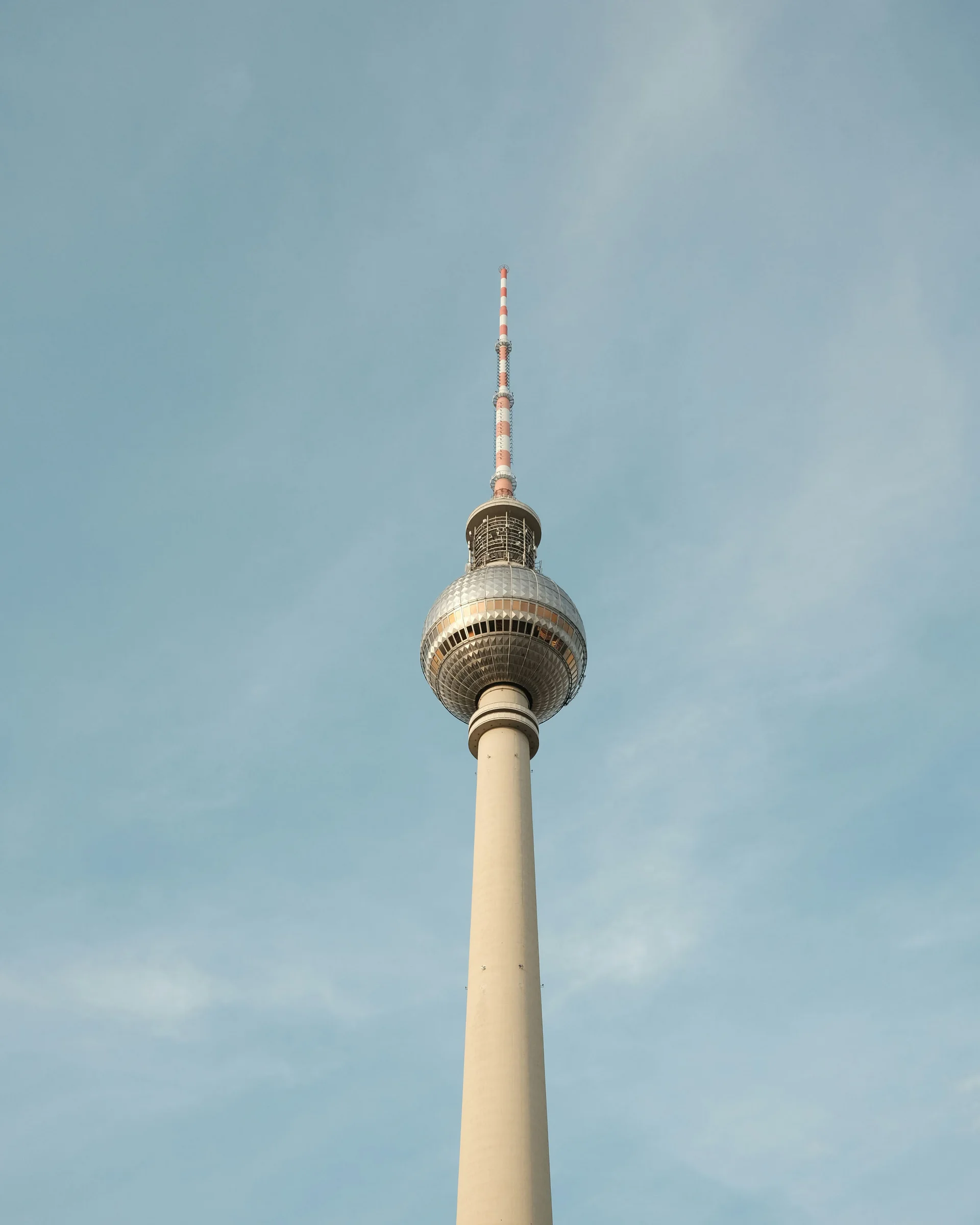 Fernsehturm mit rot-weiß gestreifter Antenne vor blauem Himmel