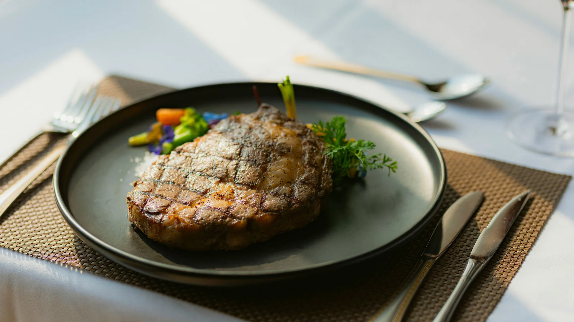 Bilder aus dem DASEYN Gegrilltes Steak auf schwarzem Teller mit Gemüse und Kräutern