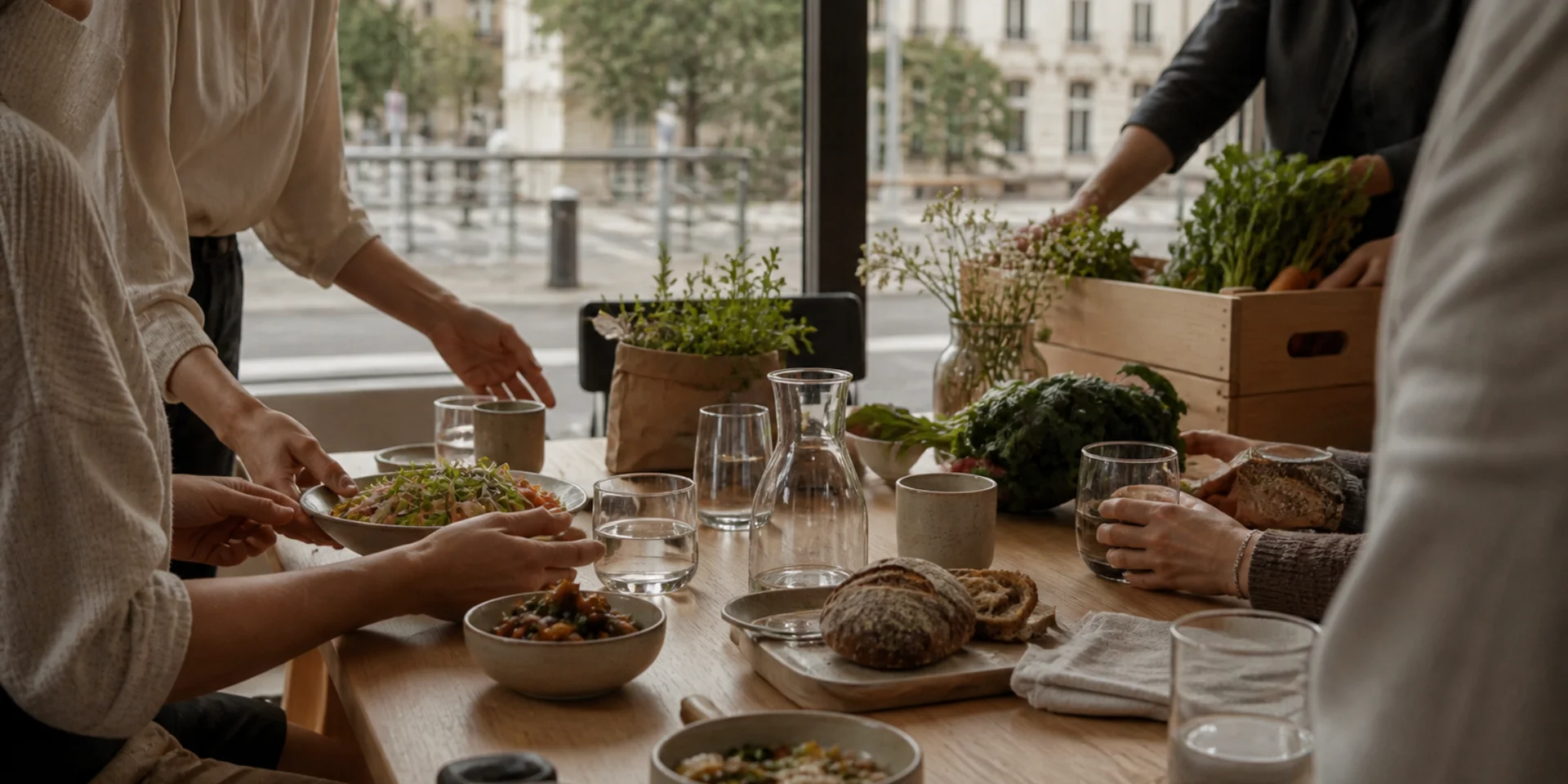Ein nachhaltiges Hotel in Deutschland: das DASEYN Menschen servieren frische Salate und Brot auf einem gedeckten Holztisch
