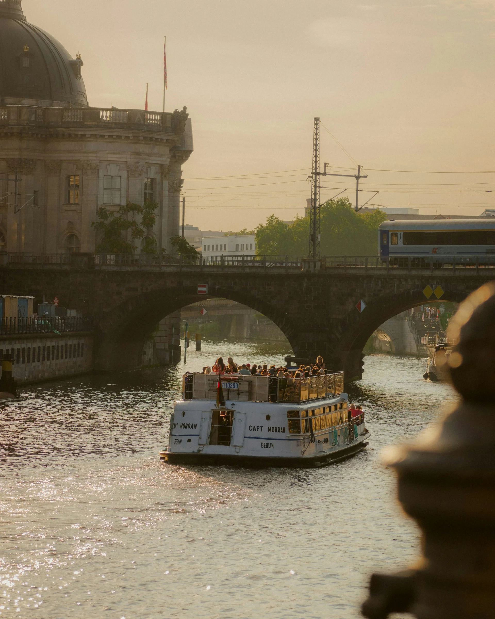 Touristenboot auf der Spree vor historischem Gebäude und Brücke bei Sonnenuntergang