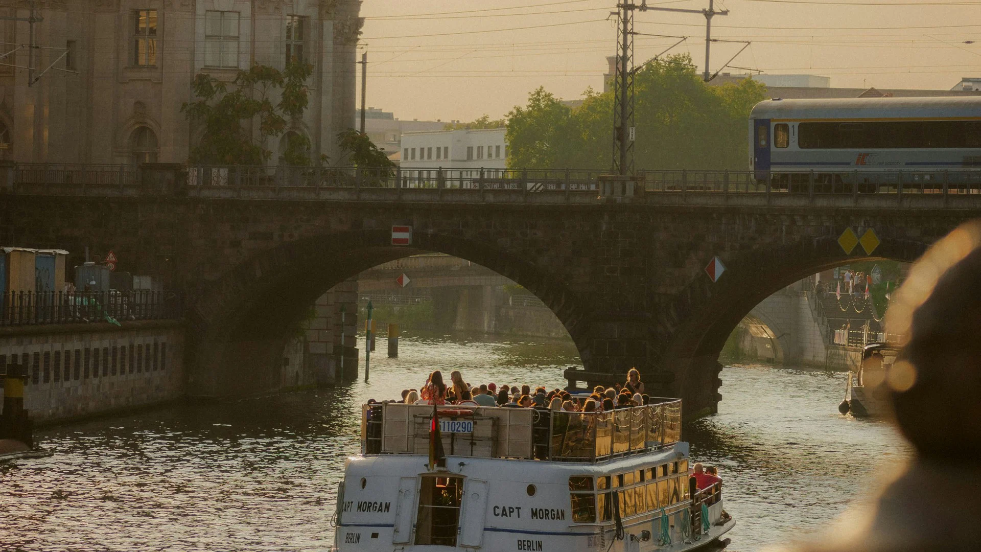 Bilder aus dem DASEYN Touristenboot auf der Spree vor historischem Gebäude und Brücke bei Sonnenuntergang
