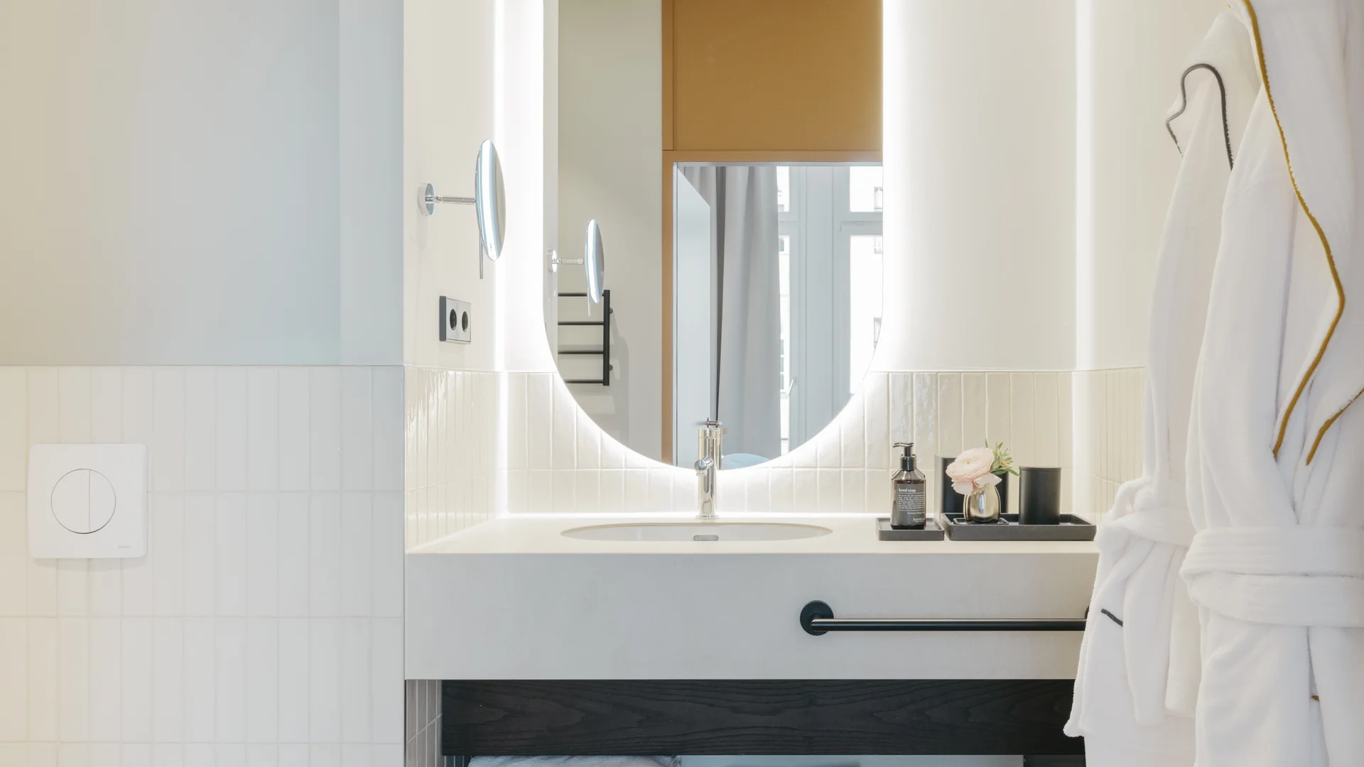 Bilder aus dem DASEYN Modernes Badezimmer mit rundem beleuchtetem Spiegel und flauschigen Bademänteln