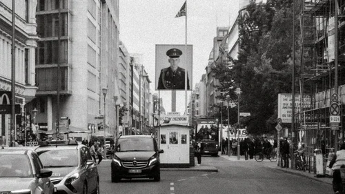 Historische Stadtstraße mit Kontrollhäuschen, Autos und großem Porträt an einer Fahnenstange