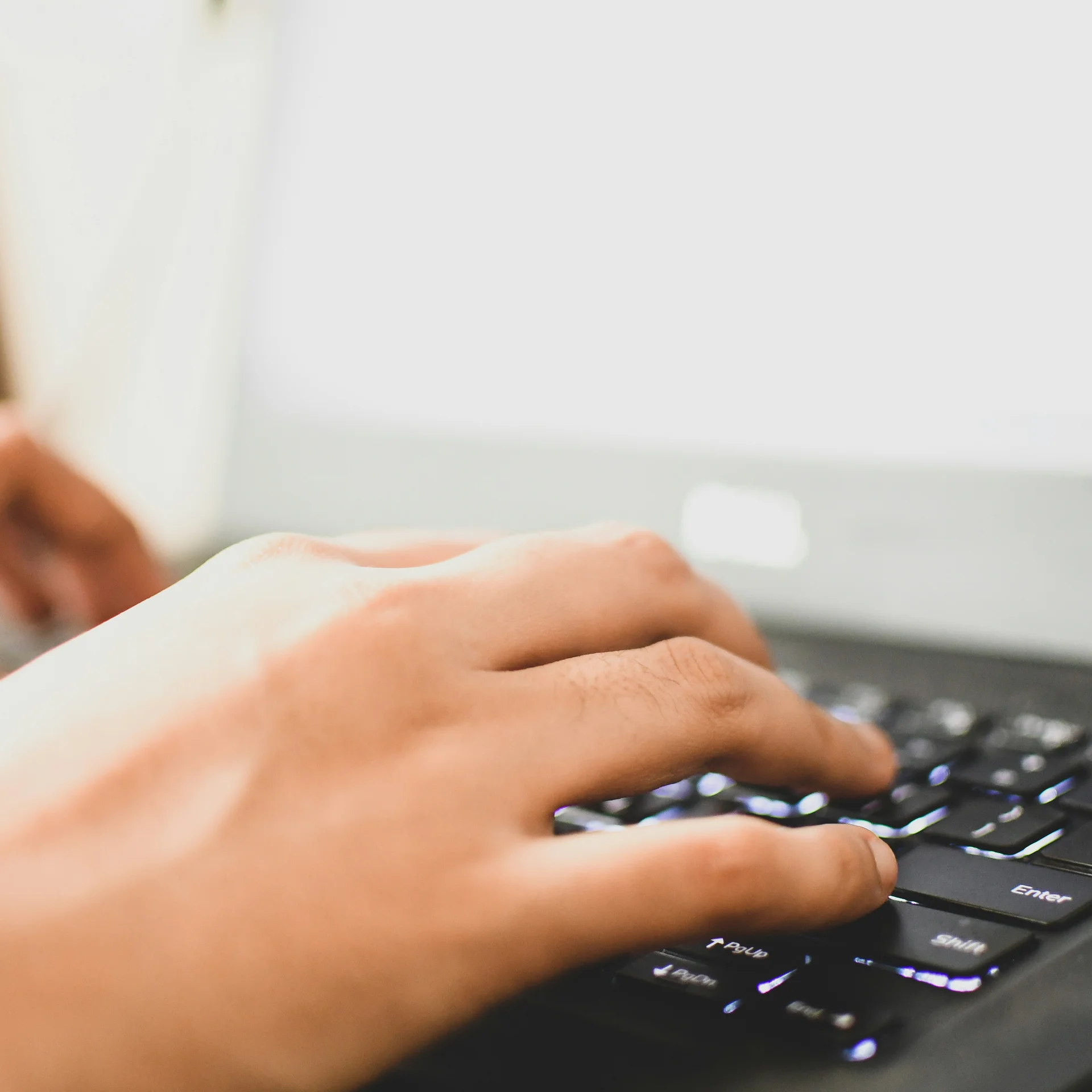 Hände tippen auf einer schwarzen Laptop-Tastatur