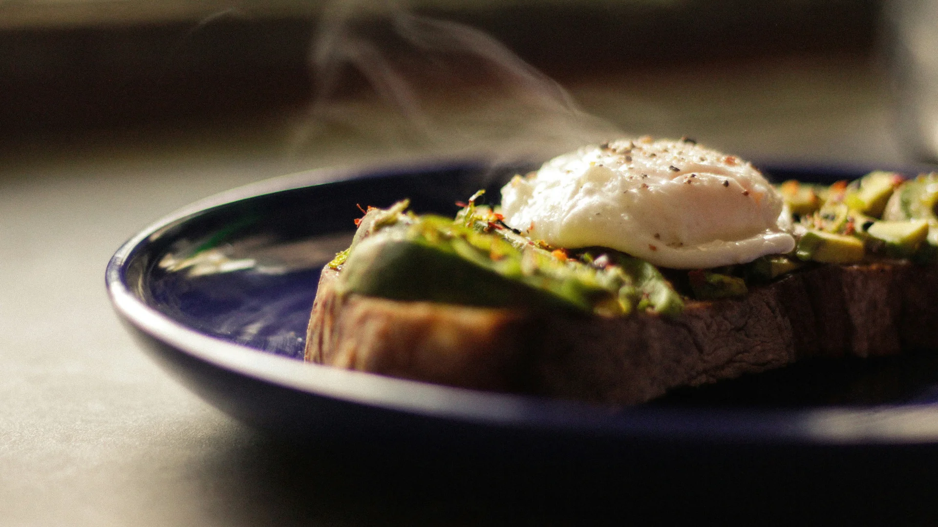 Bilder aus dem DASEYN Dampfendes Ei auf Avocado und Brot auf blauem Teller